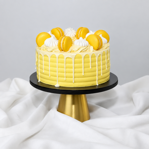 A beautifully decorated white and yellow Lemon Drizzle cake, showcasing delicate macarons and meringues, a perfect birthday cake and perfect for celebrations. Available for same-day cake delivery