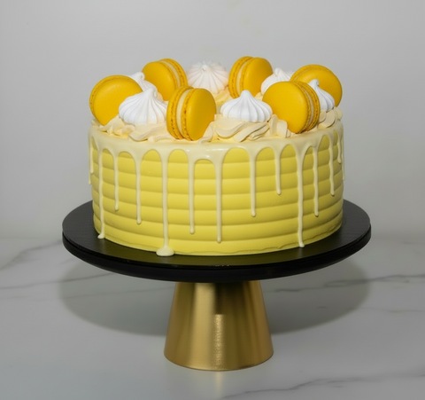 A beautifully decorated white and yellow Lemon Drizzle cake, showcasing delicate macarons and meringues, a perfect birthday cake and perfect for celebrations. Available for same-day cake delivery