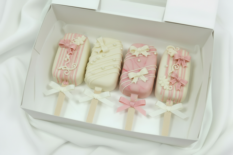 Send as a gift our beautiful set of Postal "Bows" Cakesicles! These gorgeous pink and white chocolate-coated cakesicles boast a soft and tasty centre. They make an ideal gift for birthdays and milestones. We'll deliver your delicious treats straight to your door anywhere across the UK. These beauties are a great way to happiness.